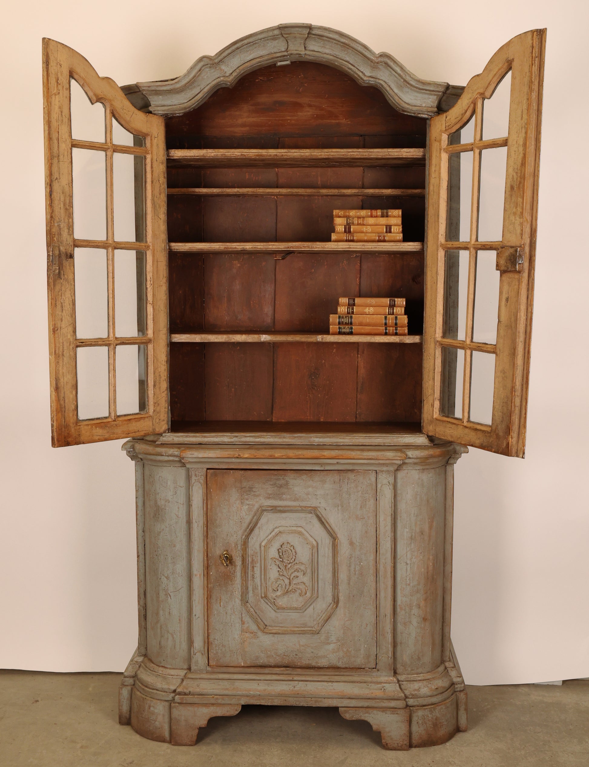 18th Century Rococo Display cabinet with opened doors that reveal decorative books. The doors also feature hand-blown glass.