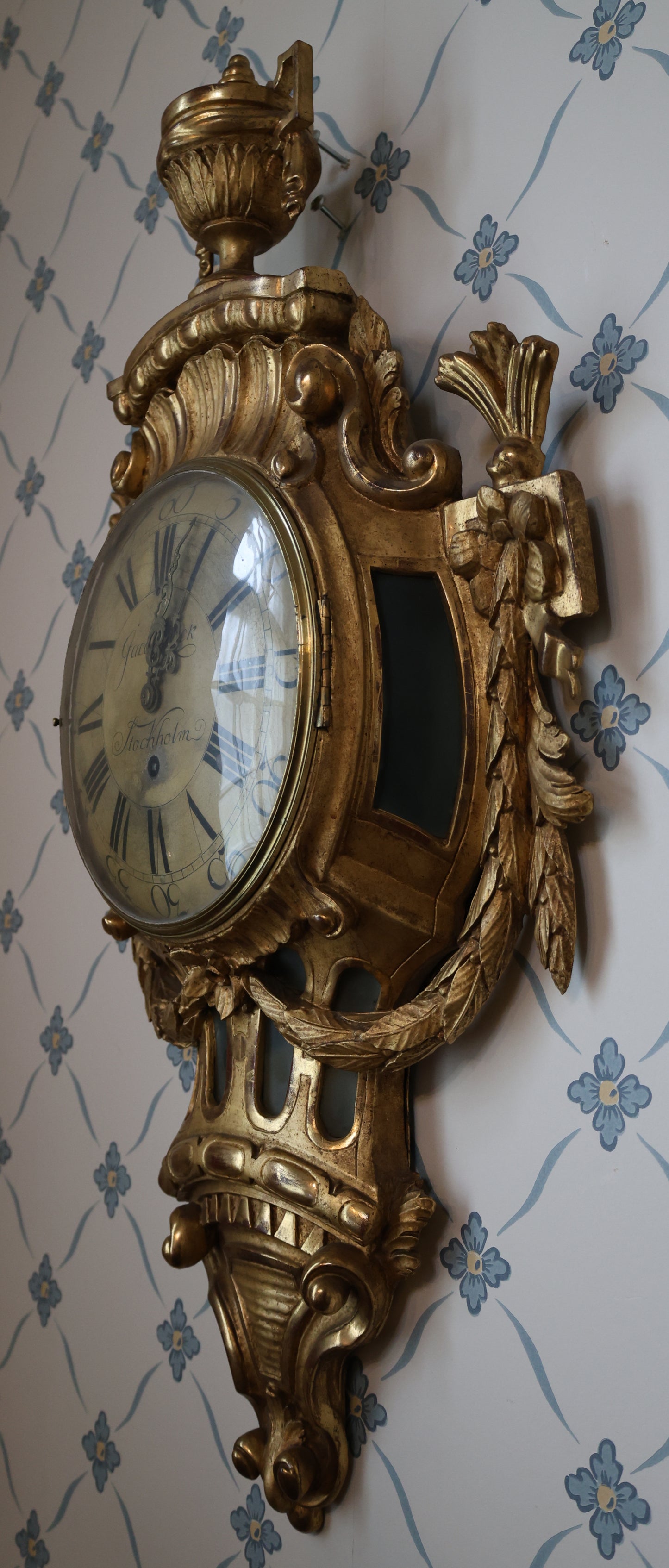 Wall Clock signed Jacob Kock from the transitional period between Rococo and Gustavian styles. The case is entirely carved from wood and gilded.