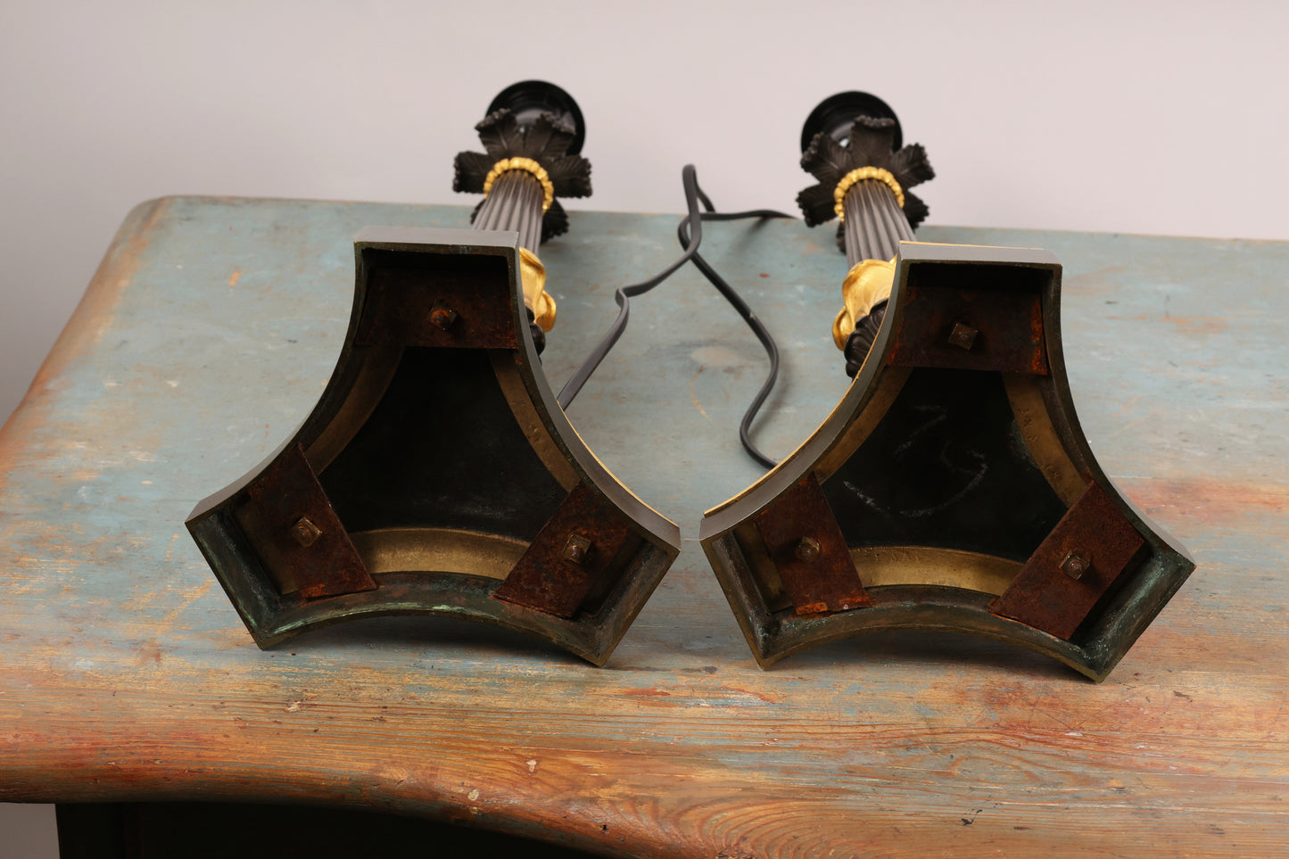 Underneath a pair of dark patinated and burnished gilded Charles X lamp bases from the 19th century.