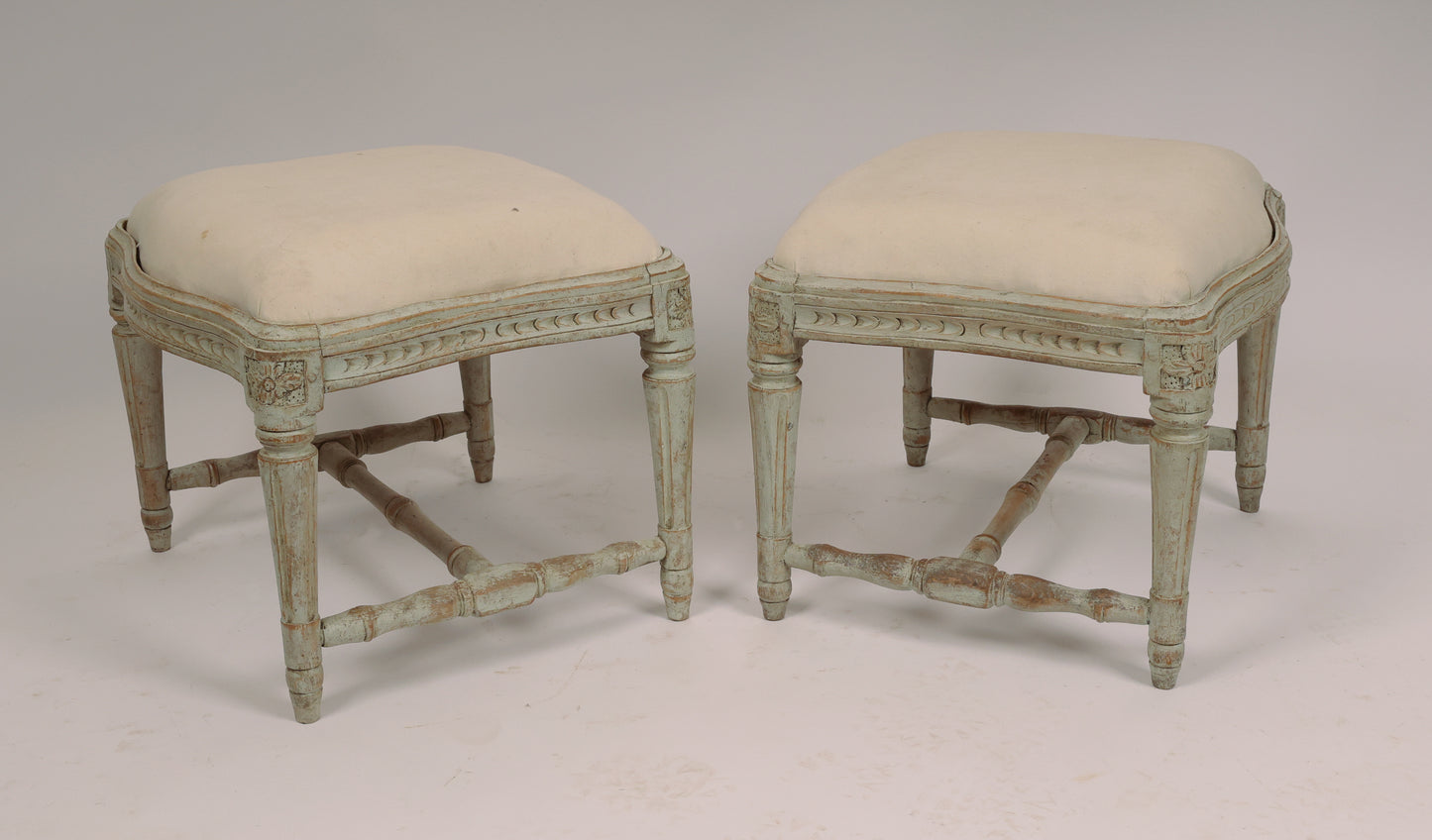 A pair of beautiful Swedish stools made in Stockholm. The convex and concave edges are not so common. The stools have elegant wood carvings where the corner florons have spikes. The pattern on the sides is unusual. The legs, which are stabilized by an H-cross, have fine flutes. The seats are removable.