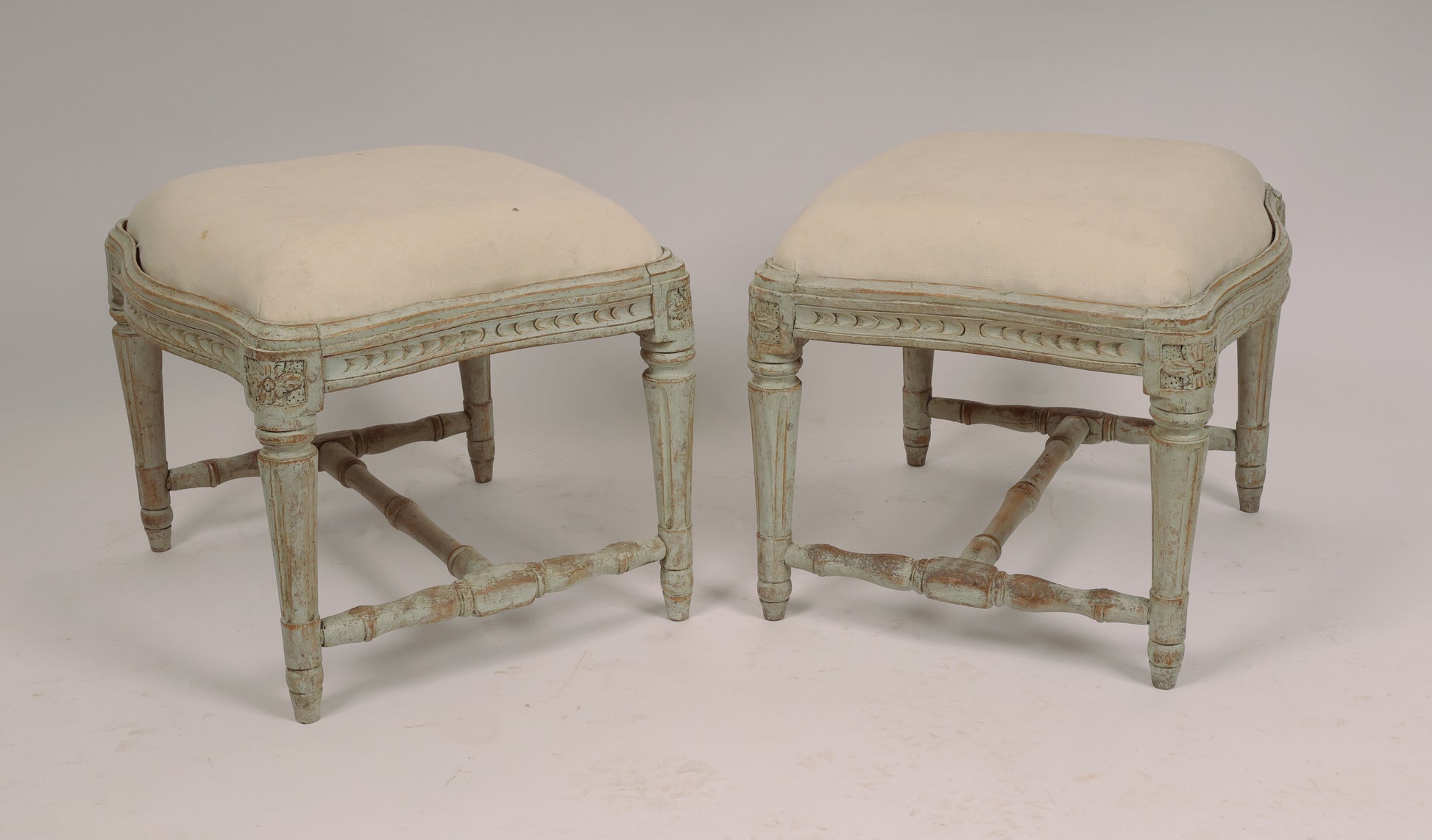 A pair of beautiful Swedish stools made in Stockholm. The convex and concave edges are not so common. The stools have elegant wood carvings where the corner florons have spikes. The pattern on the sides is unusual. The legs, which are stabilized by an H-cross, have fine flutes. The seats are removable.