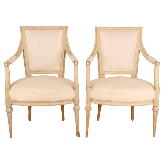 A pair of antique armchairs from the Gustavian era. They are from the 18th century and are grey with white upholstery.