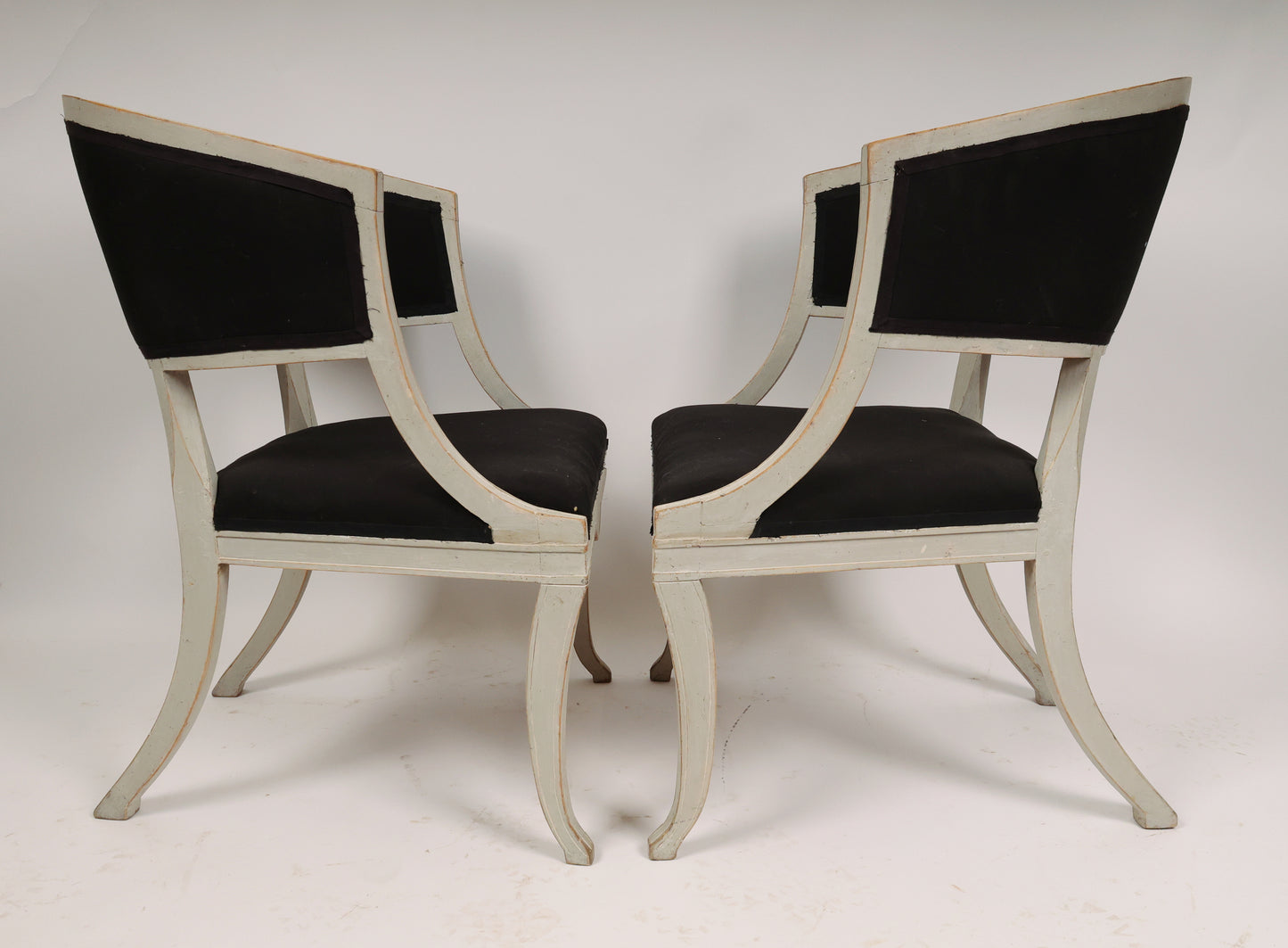 Side view of a Pair of Early 19th Century Empire Armchairs facing each other. The antique chairs are grey with black fabric.