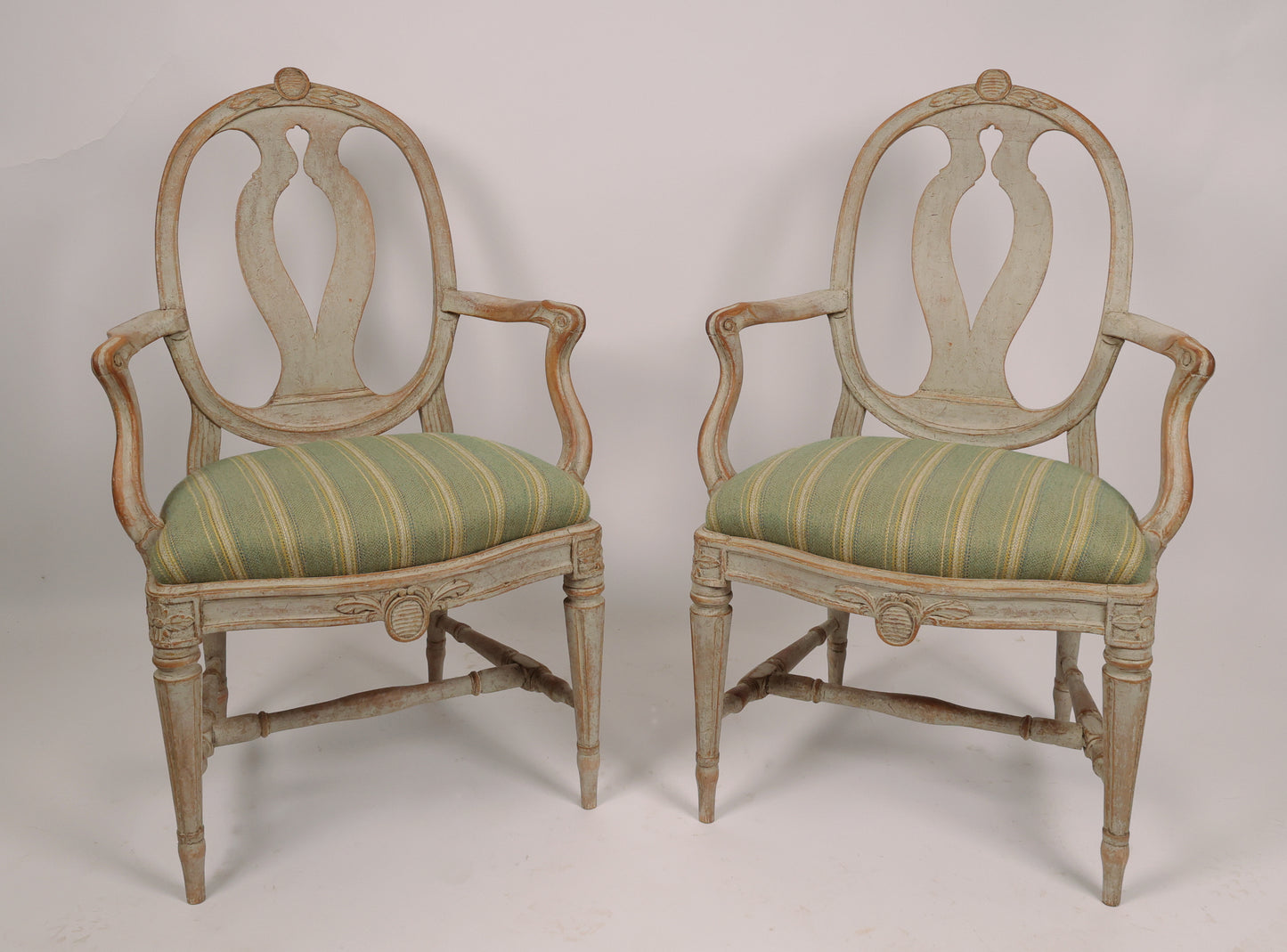 Front view of 18th Century Gustavian Armchairs Signed Johan Eric Höglander (Sweden, 1750-1813) and with the Stockholm chairmaker's seal. The chairs have pearl gray original color. The wood carvings of the armchairs are of the highest quality with flowers, shields and French flutings.