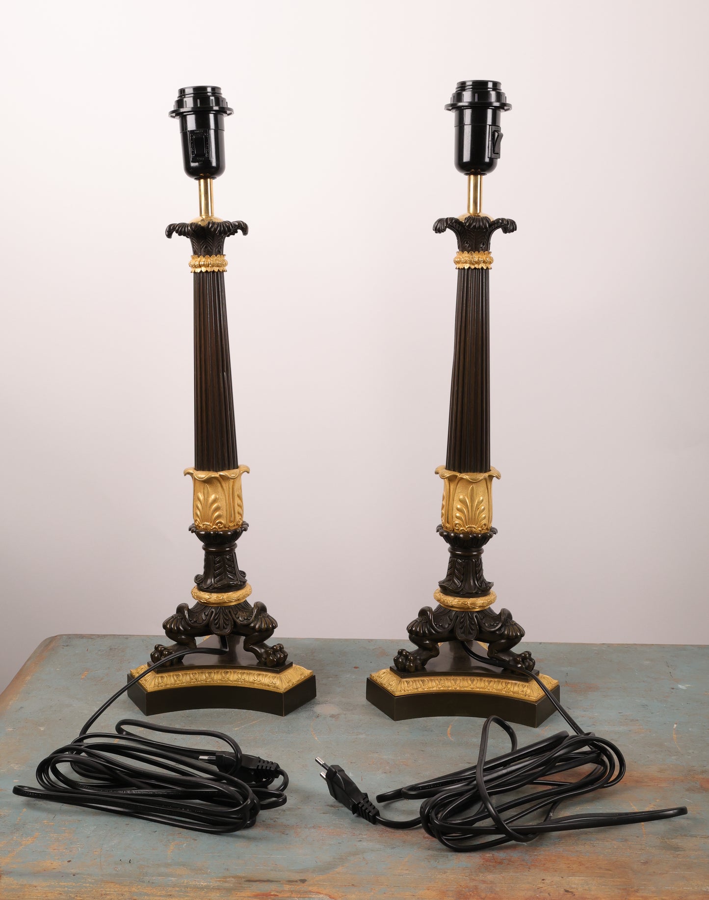 A pair of beautifully crafted lamp bases, French, from the 1830s in the Charles X style. Originally, they were a pair of candelabras that have since been converted. They are made of fire-gilded bronze with black patinated details. The lamps have been rewired to meet European standards. They are in good condition.