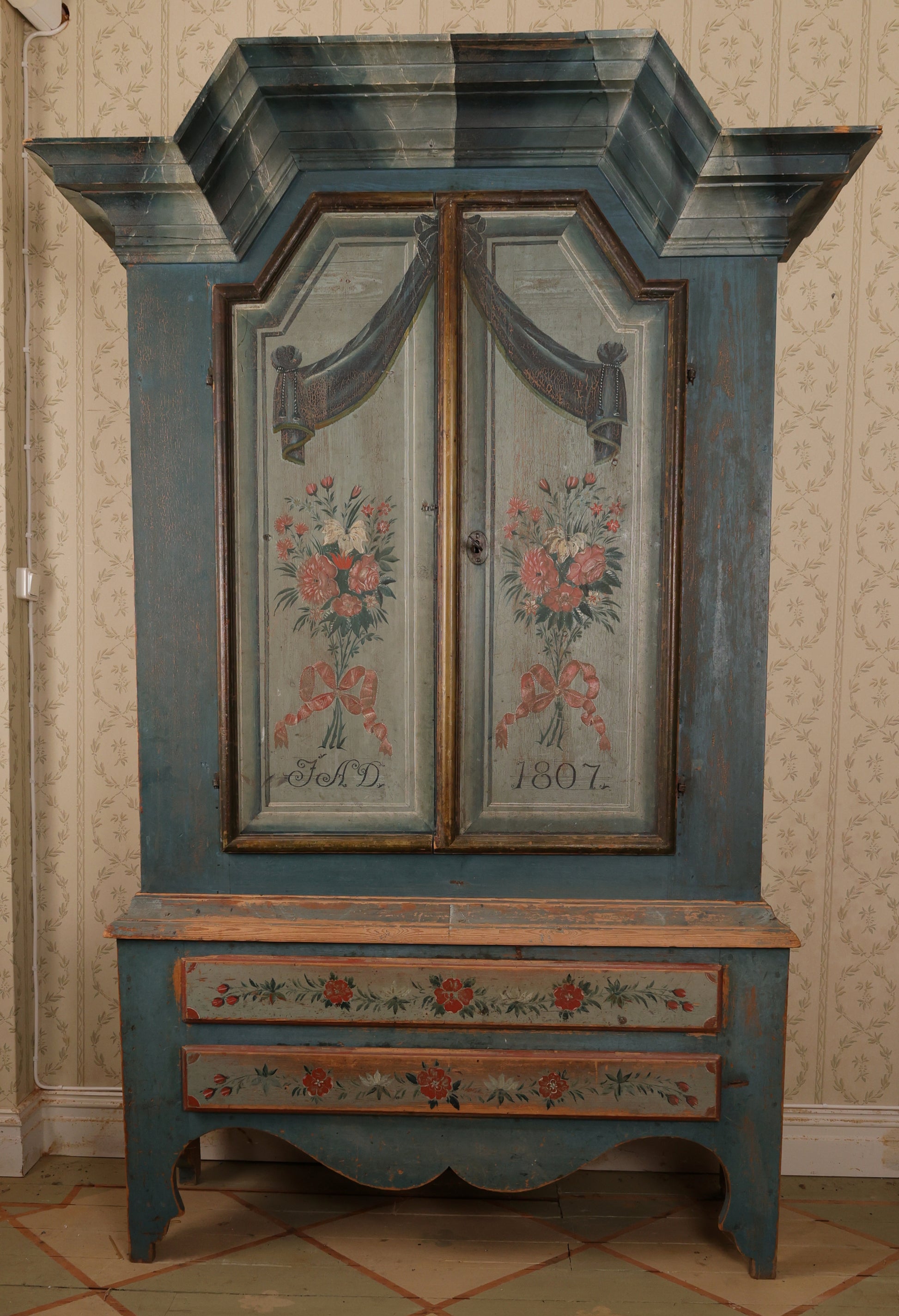 Full view of an antique blue cabinet from the 19th century with painted flowers.