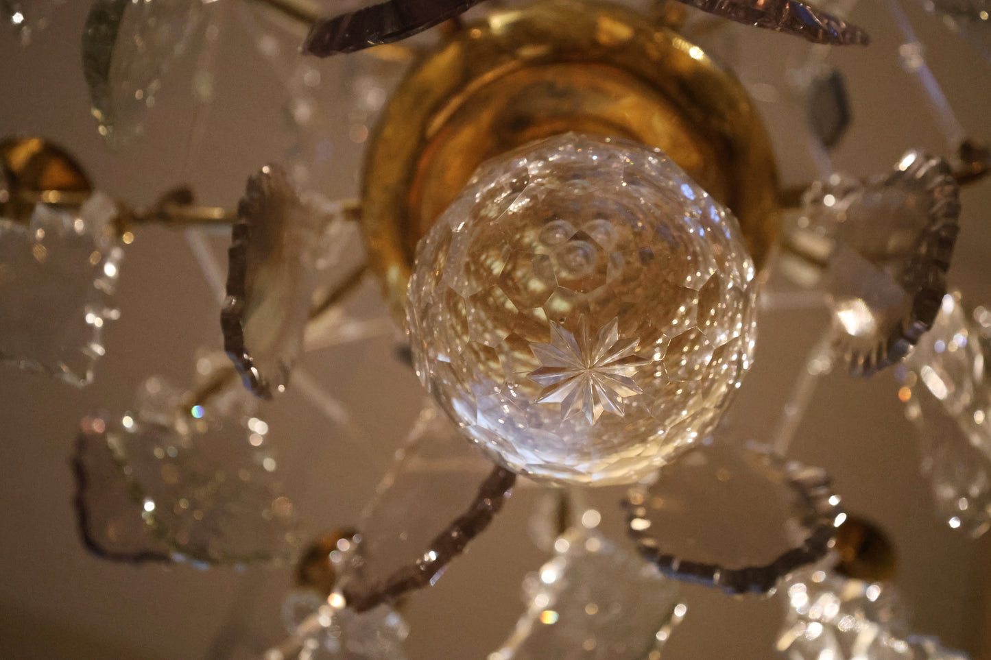 At the bottom of an 18th century rococo chandelier is a cut glass ball. The chandelier also includes decorative glass rods.