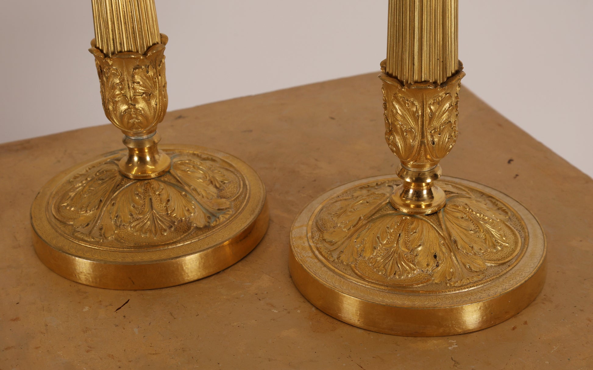 Close up of the bases of a pair of empire candleholders in bronze