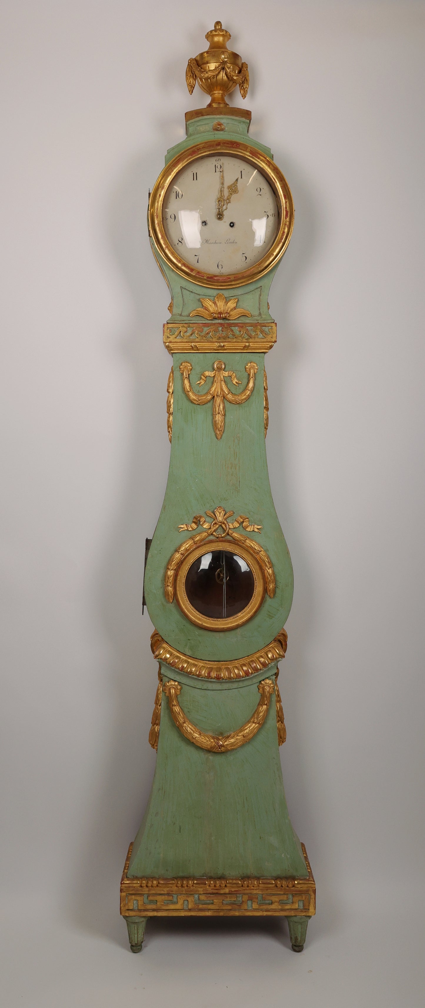 Fantastic Swedish Gustavian longcase clock. The case is a Stockholm work from around 1770/1780. It is lacquered and gilded with rich wood-carved details of, among other things, garlands, flowers, an urn and the "running dog" ornament type. The clockwork is a high-class London work by Marckam. The hood and body have original blown glass.