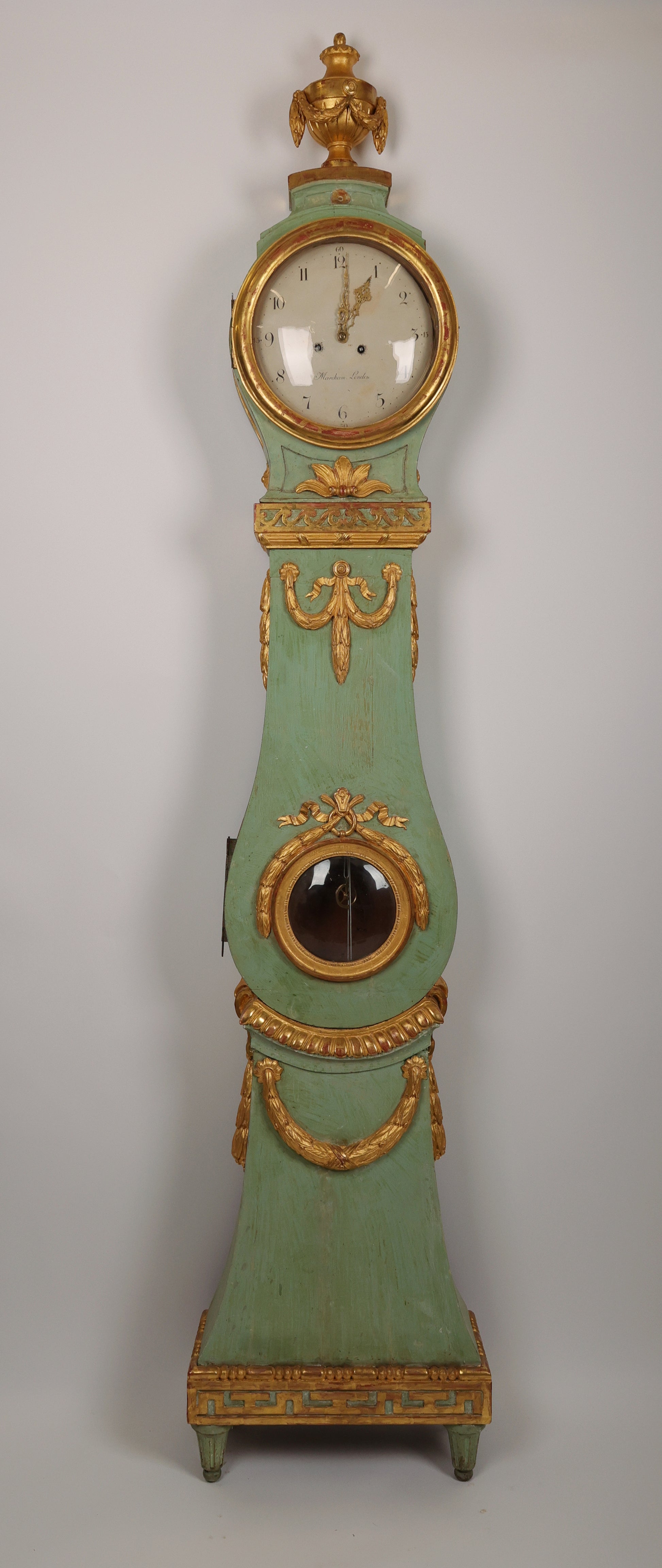 Fantastic Swedish Gustavian longcase clock. The case is a Stockholm work from around 1770/1780. It is lacquered and gilded with rich wood-carved details of, among other things, garlands, flowers, an urn and the "running dog" ornament type. The clockwork is a high-class London work by Marckam. The hood and body have original blown glass.