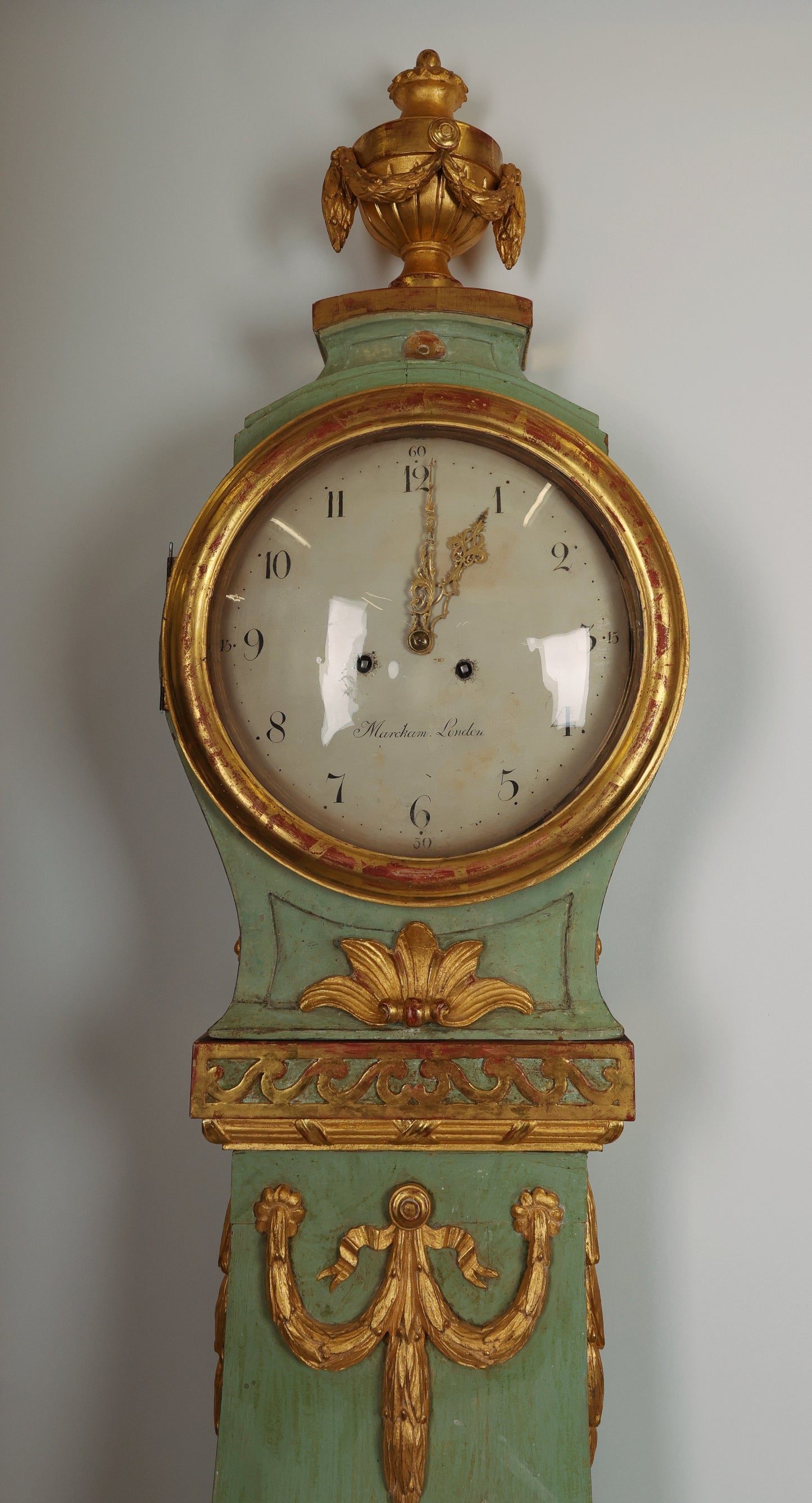 Close up view of 18th Century Gustavian Longcase Clock in green color and lacquered and gilded with rich wood-carved details