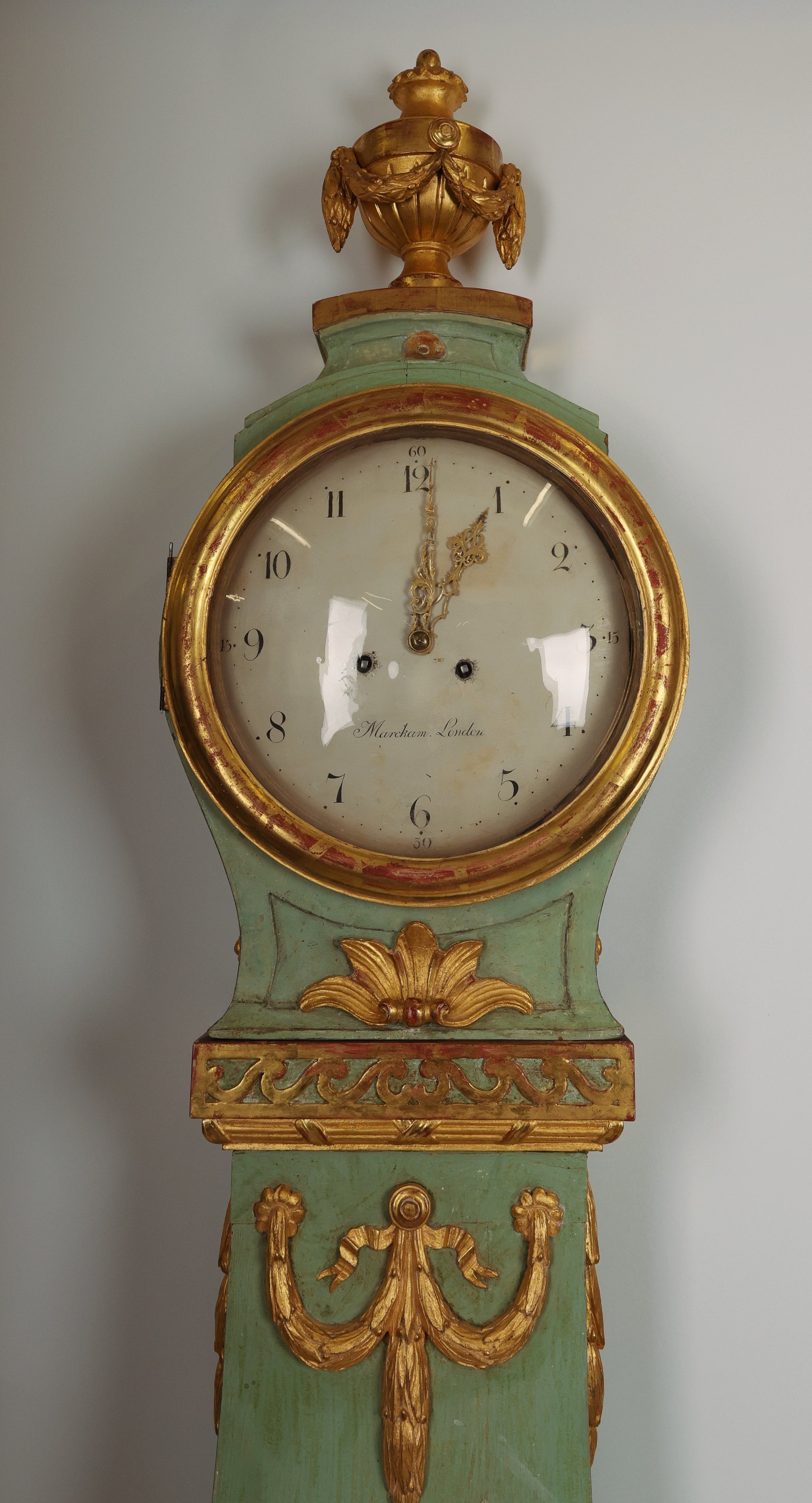 Close up view of 18th Century Gustavian Longcase Clock in green color and lacquered and gilded with rich wood-carved details