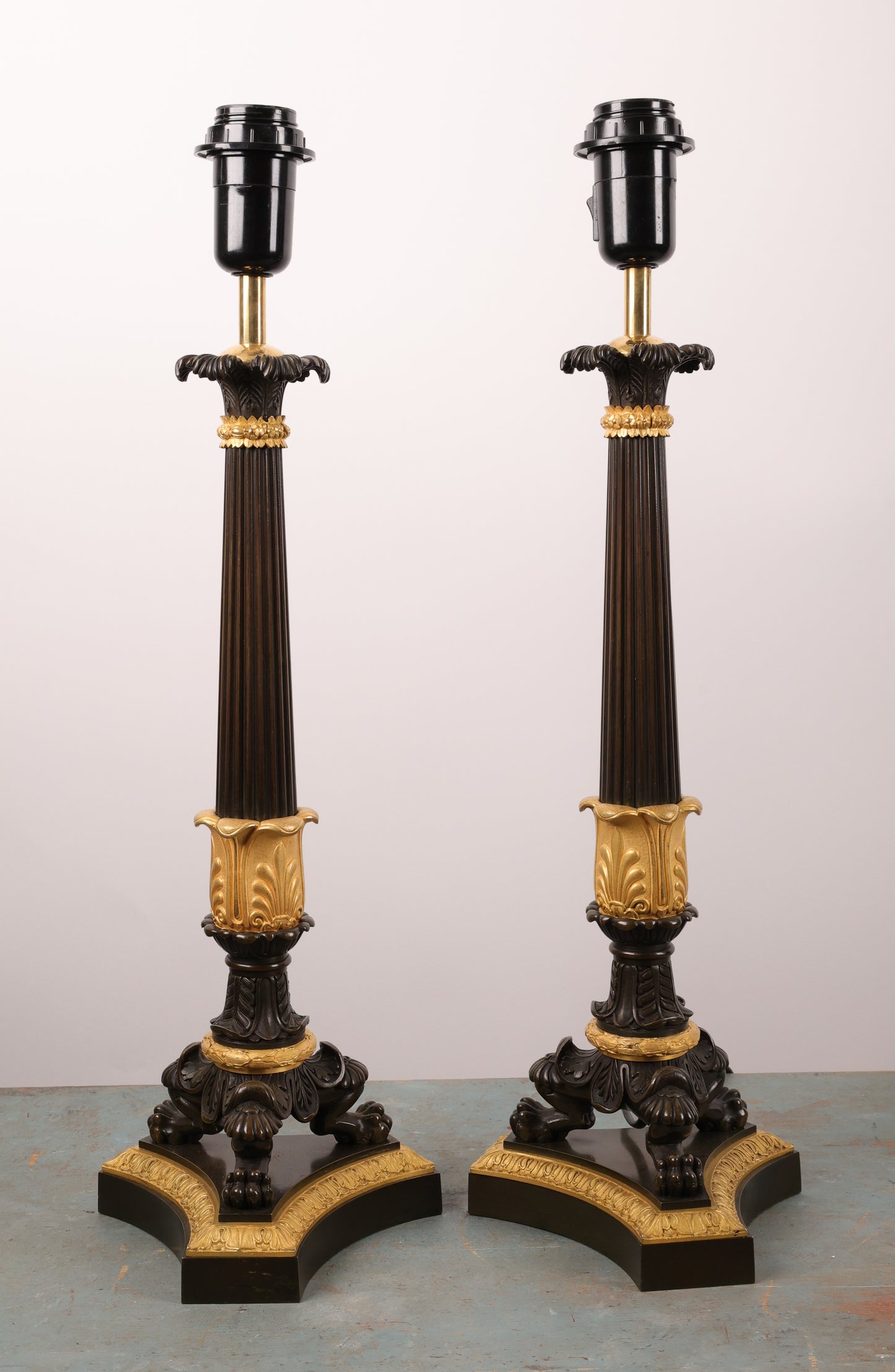 A pair of beautifully crafted lamp bases, French, from the 1830s in the Charles X style. Originally, they were a pair of candelabras that have since been converted. They are made of fire-gilded bronze with black patinated details. The lamps have been rewired to meet European standards. They are in good condition.