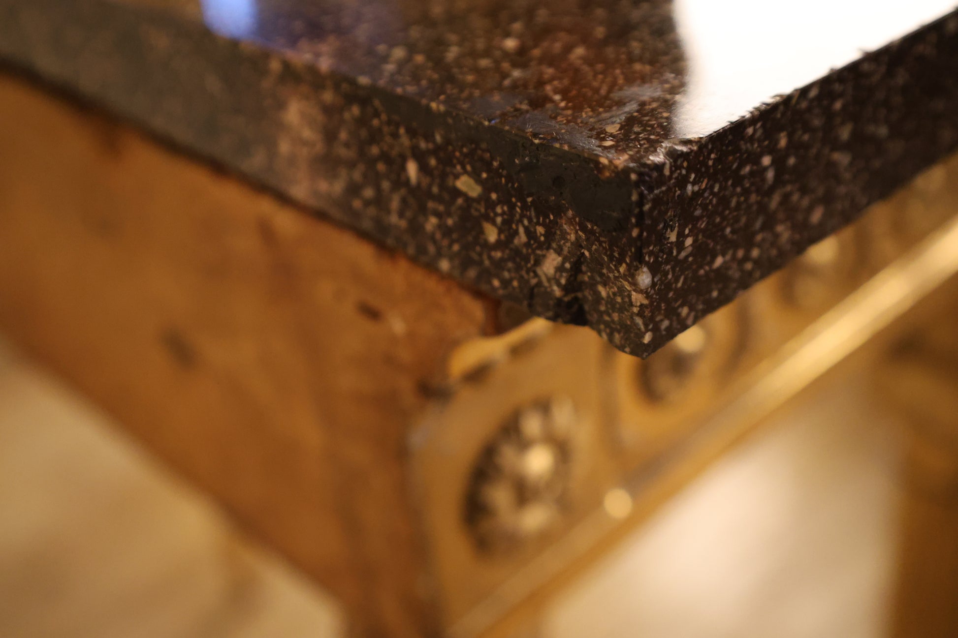 A close up of a porphyry top on a gilt console table.