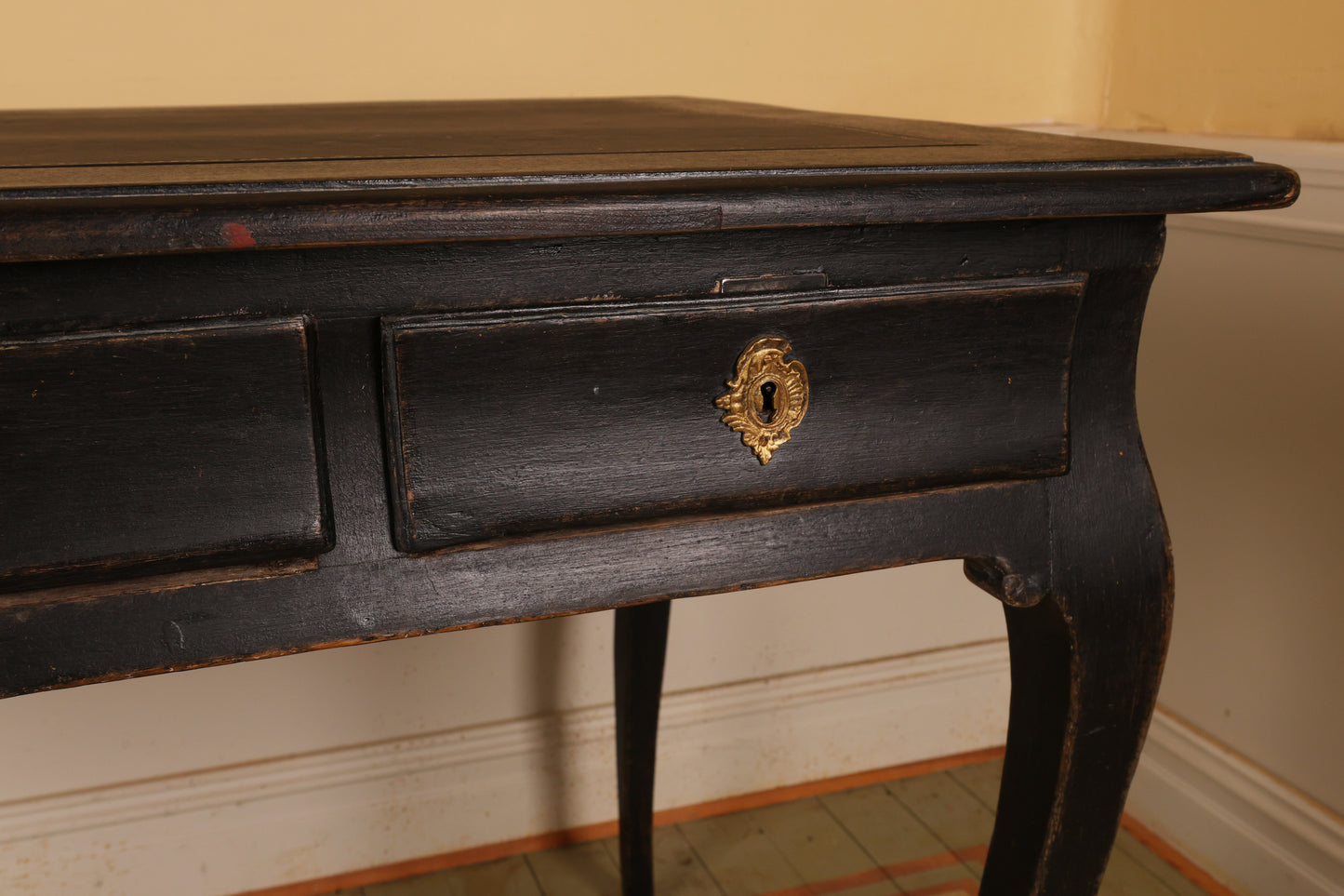 Detail of a beautifully crafted Rococo writing desk from the 18th century featuring gracefully curved legs and one of three finely vaulted drawers.