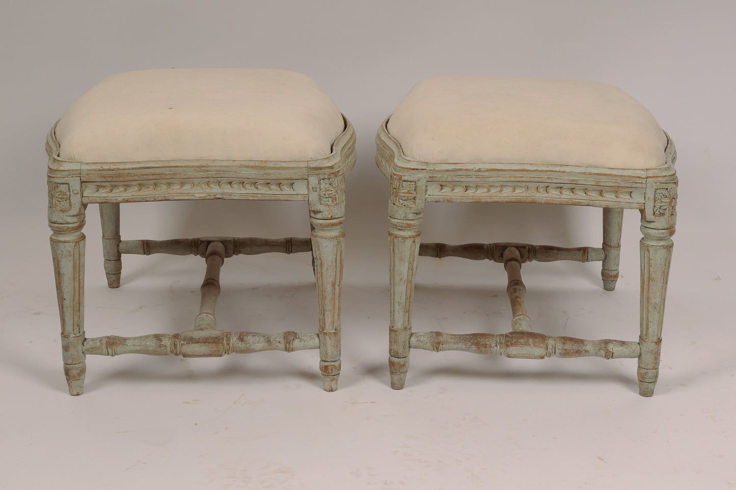 A pair of beautiful Swedish stools made in Stockholm. The convex and concave edges are not so common. The stools have elegant wood carvings where the corner florons have spikes. The pattern on the sides is unusual. The legs, which are stabilized by an H-cross, have fine flutes. The seats are removable.
