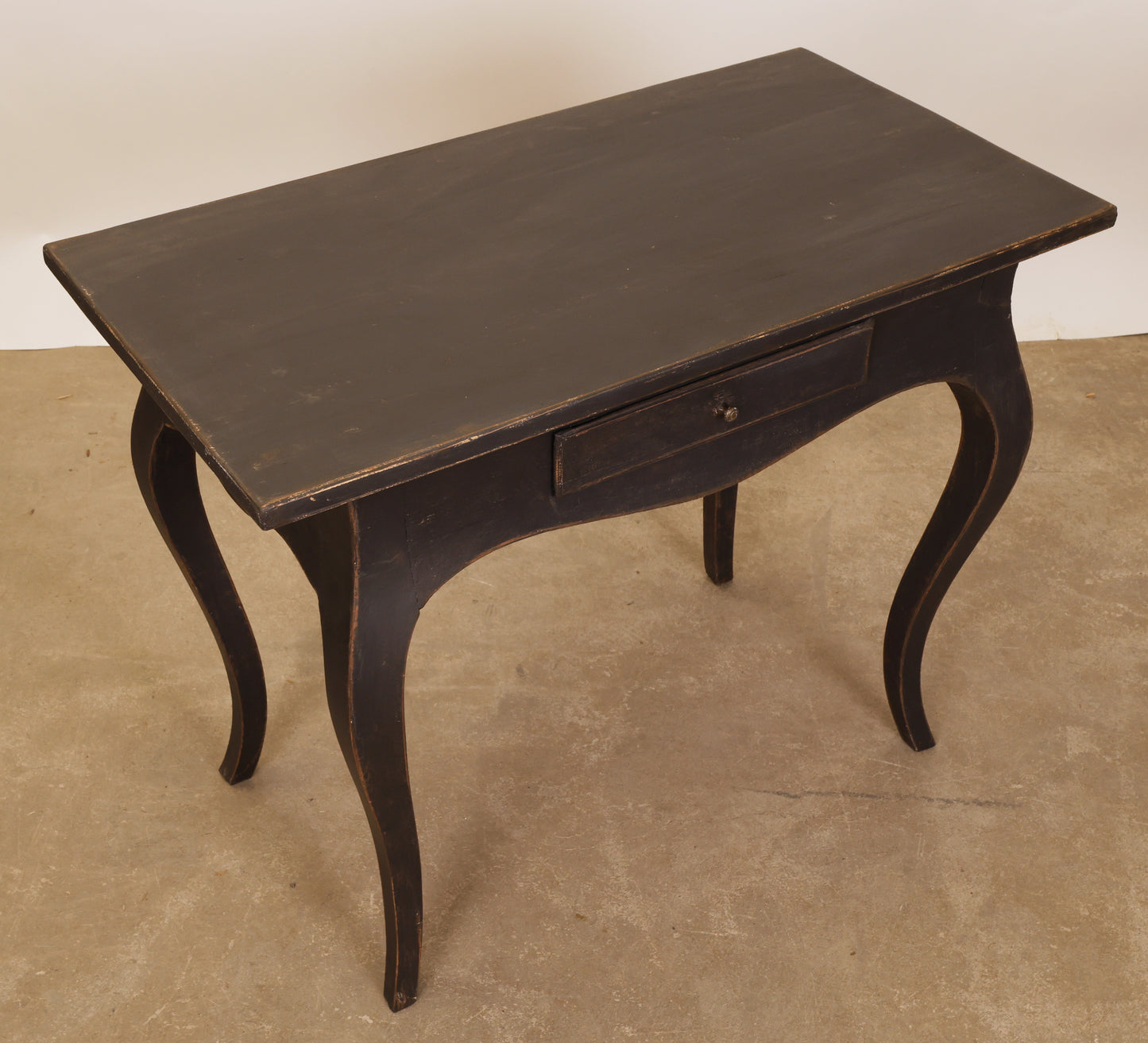 An antique black Rococo table with a drawer.