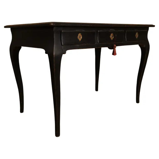 Beautifully crafted Rococo writing desk from the 18th century featuring gracefully curved legs and three finely vaulted drawers, which open with accompanying key. The key escutcheons are made of gilded bronze in early Rococo forms. The top is later fitted with leader, adorned with gilded edges. With white background.