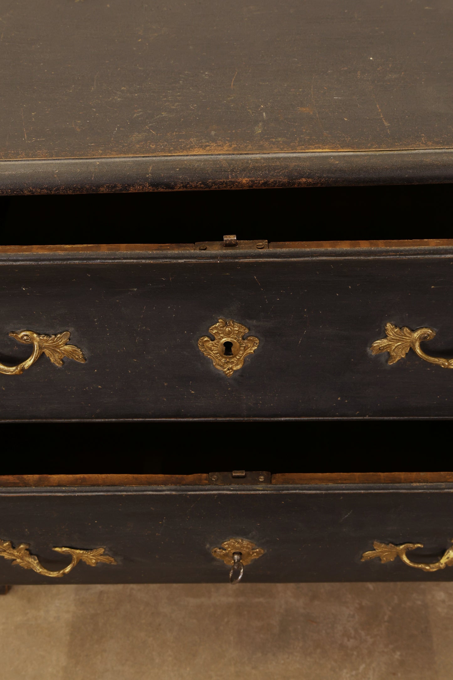 Close-up of a black Rococo chest of drawers with gold decorative elements