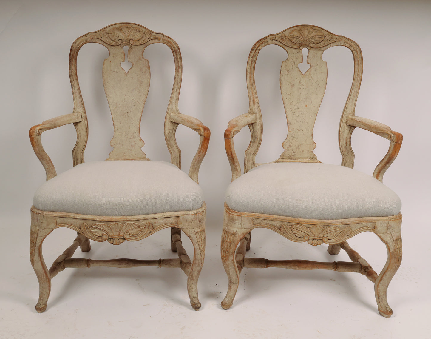 A pair of Rococo armchairs made in Stockholm around 1760/70. Featuring carvings of rocailles with pickering in both the apron and the back. The chairs are equipped with H-stretchers and have removable upholstered seats.