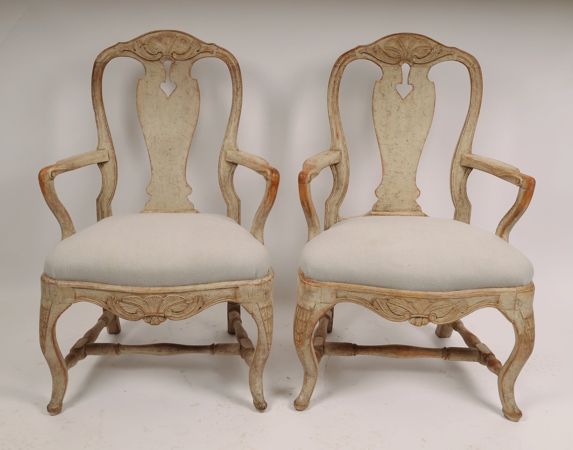 A pair of Rococo armchairs made in Stockholm around 1760/70. Featuring carvings of rocailles with pickering in both the apron and the back. The chairs are equipped with H-stretchers and have removable upholstered seats.