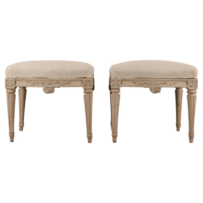 A pair of high-quality Gustavian works from Stockholm, signed by Johan Erik Höglander (Sweden, 1750-1813). The stools are elegantly curved on all sides, adding extra sophistication. They feature carved decorations of grapes and branches, as well as corner rosettes. The legs are carved with fluting. White background.