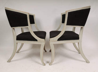 Side view of a Pair of Early 19th Century Empire Armchairs facing each other. The antique chairs are grey with black fabric. 
