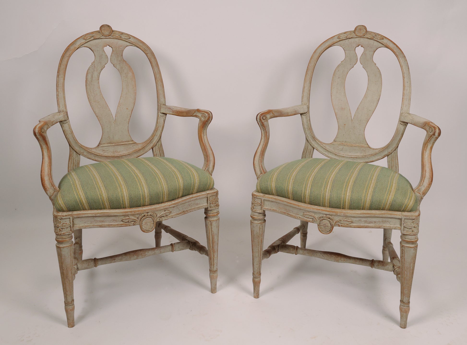 Front view of 18th Century Gustavian Armchairs Signed Johan Eric Höglander (Sweden, 1750-1813) and with the Stockholm chairmaker's seal. The chairs have pearl gray original color. The wood carvings of the armchairs are of the highest quality with flowers, shields and French flutings.
