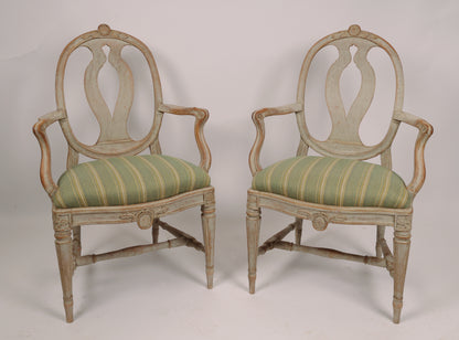 Front view of 18th Century Gustavian Armchairs Signed Johan Eric Höglander (Sweden, 1750-1813) and with the Stockholm chairmaker's seal. The chairs have pearl gray original color. The wood carvings of the armchairs are of the highest quality with flowers, shields and French flutings.