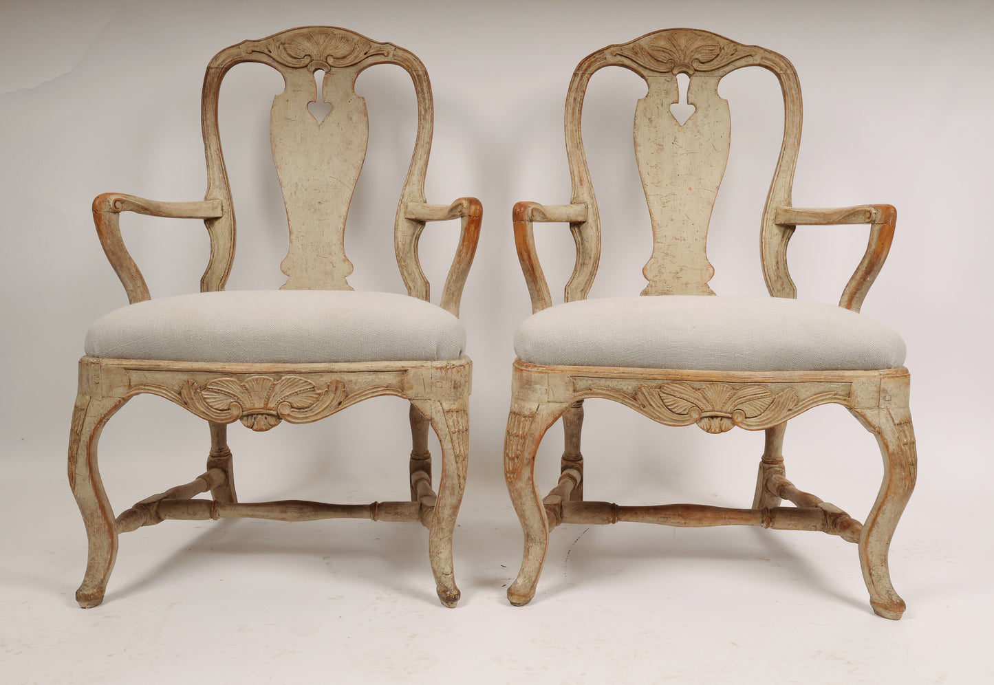 A pair of Rococo armchairs made in Stockholm around 1760/70. Featuring carvings of rocailles with pickering in both the apron and the back. The chairs are equipped with H-stretchers and have removable upholstered seats.