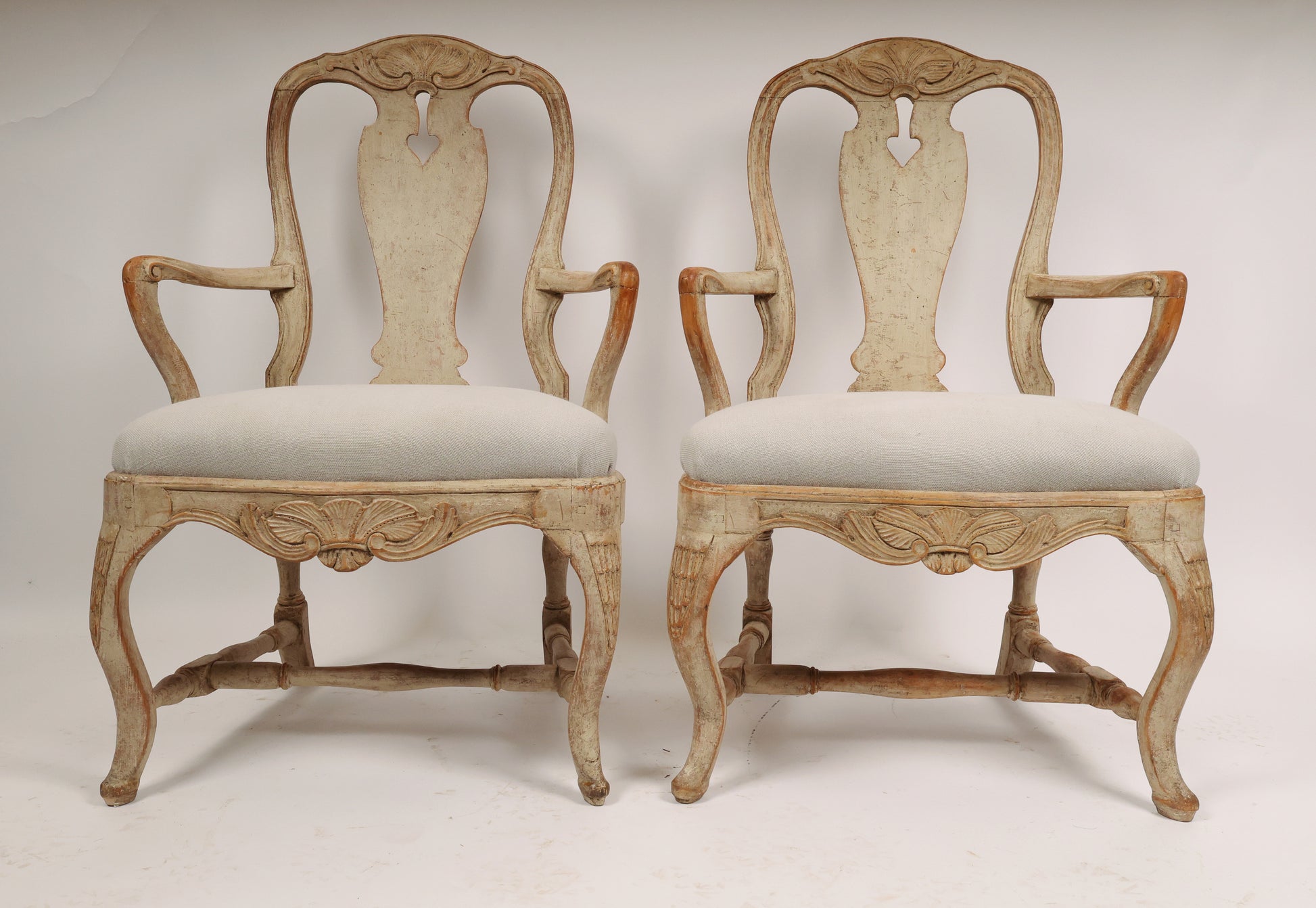 A pair of Rococo armchairs made in Stockholm around 1760/70. Featuring carvings of rocailles with pickering in both the apron and the back. The chairs are equipped with H-stretchers and have removable upholstered seats.