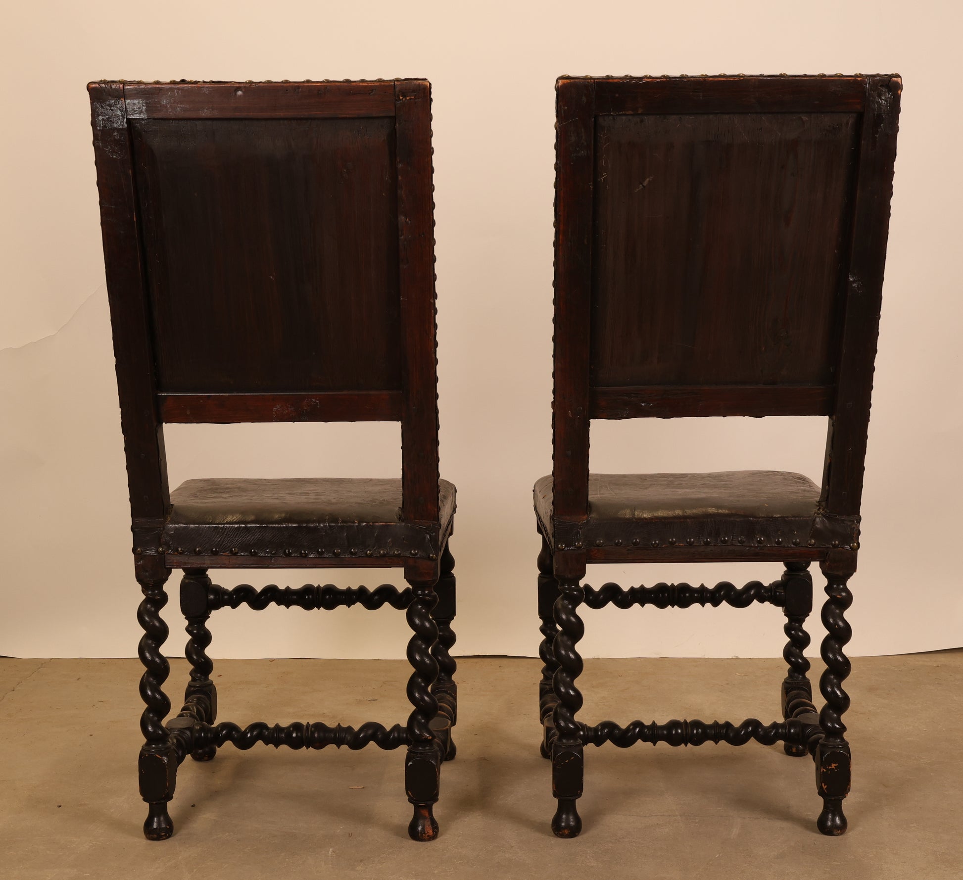 The backview of a pair of black Baroque antique chairs.