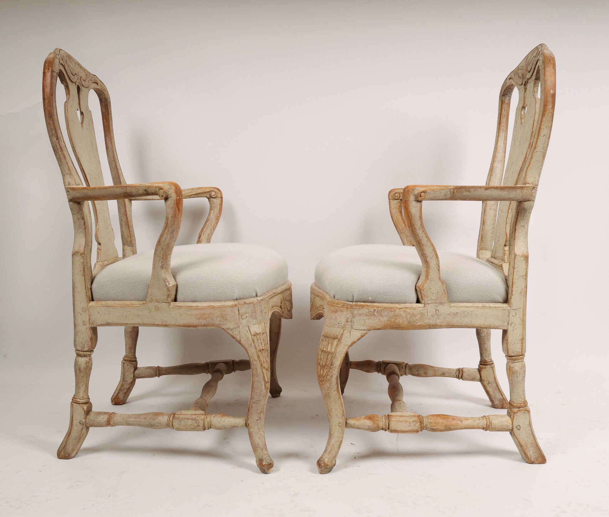 Two grey and white 18th century Rococo armchairs facing each other.
