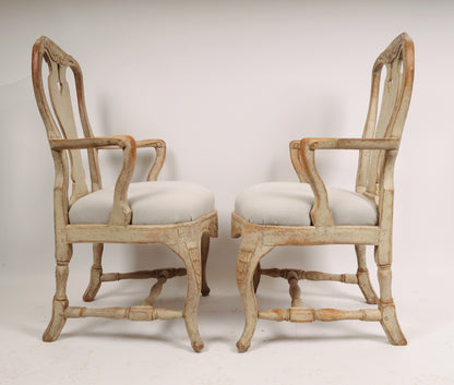 Two grey and white 18th century Rococo armchairs facing each other.