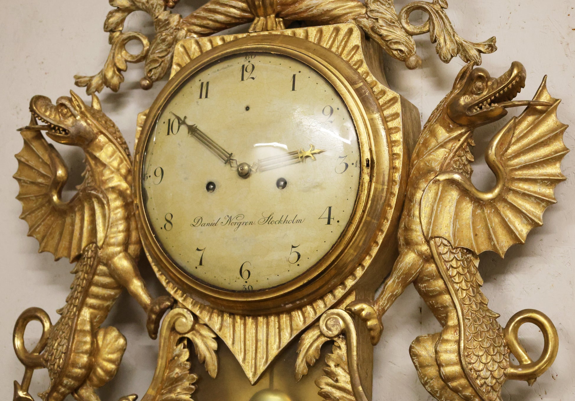 Gilded dragons on an antique wall clock from the Empire epoch.