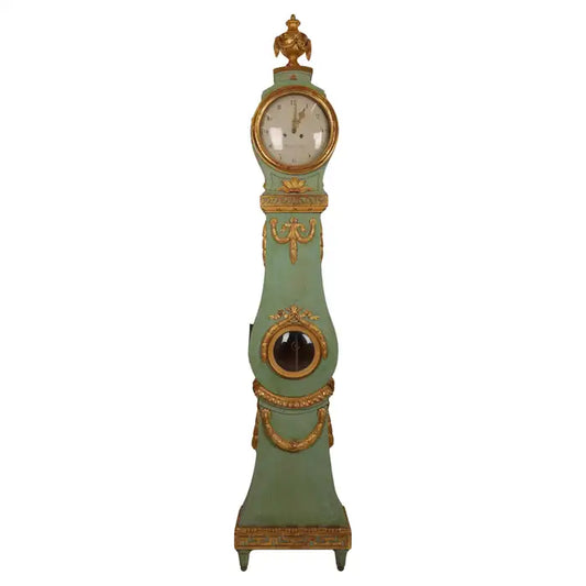 Fantastic Swedish Gustavian longcase clock. The case is a Stockholm work from around 1770/1780. It is lacquered and gilded with rich wood-carved details of, among other things, garlands, flowers, an urn and the "running dog" ornament type. The clockwork is a high-class London work by Marckam. The hood and body have original blown glass. White background.