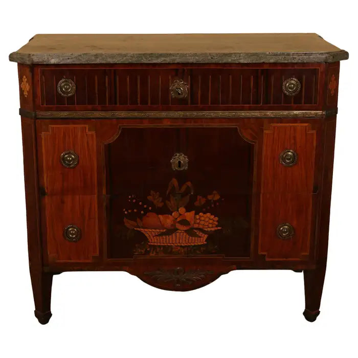 A distinguished high-Gustavian commode, crafted in Stockholm by Gustaf Foltjern (master 1771-1804). The top features an original slab of Kolsmo marble, while the body is veneered in various woods on a frame of pine and alder. The front is adorned with exquisite intarsia work, including a fruit basket design, and the inlay is meticulously engraved with wax. The upper drawer features illusory inlaid cannelures. The body is straight with angled corners, beautifully decorated with fleurons. White background.