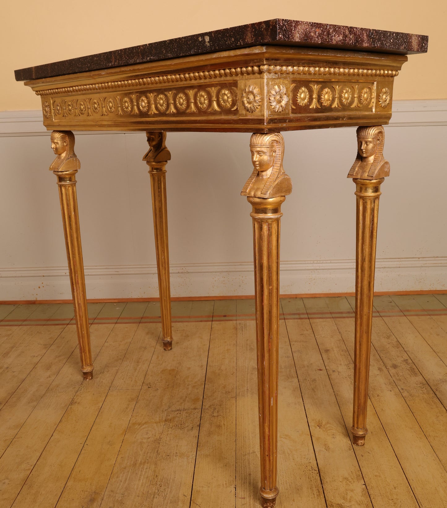 Side view a gilded high-quality Gustavian console table made in Stockholm in the 19th century. The legs feature carved Egyptian-inspired heads and fluted details.