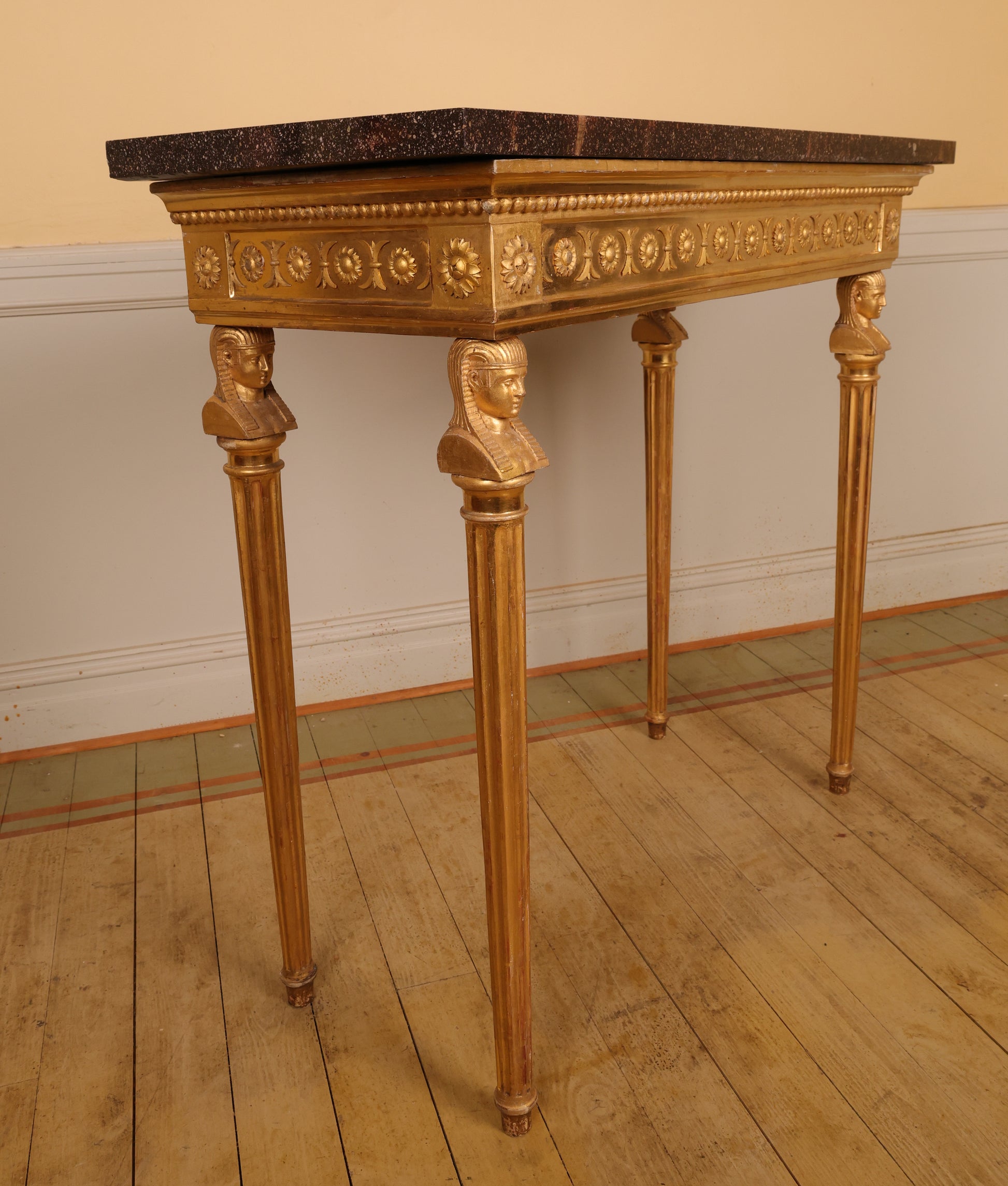Side view of a gilded high-quality Gustavian console table made in Stockholm in the 19th century. The legs feature carved Egyptian-inspired heads and fluted details.