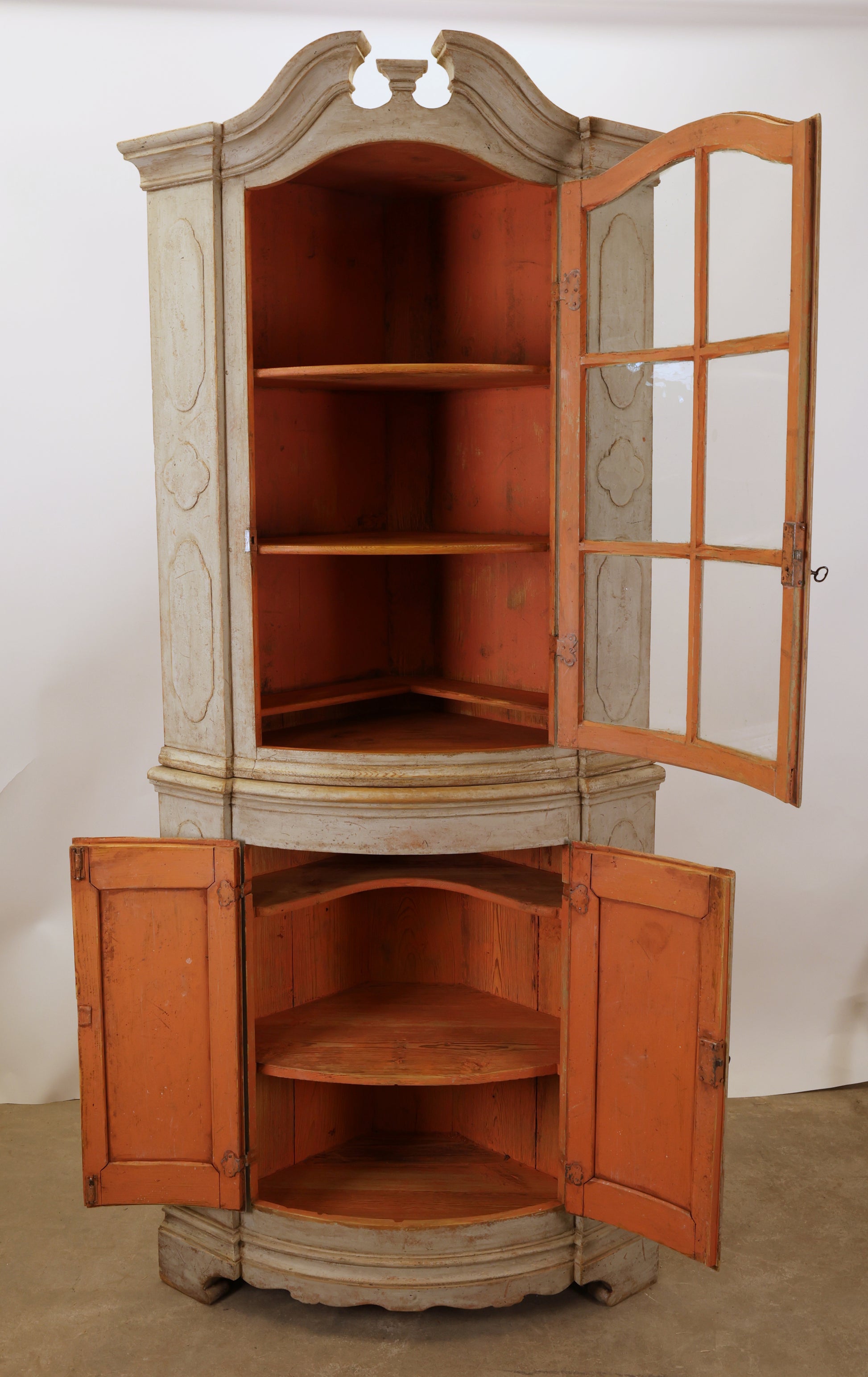 A Rococo corner cabinet with opened doors, displaying the shelves.