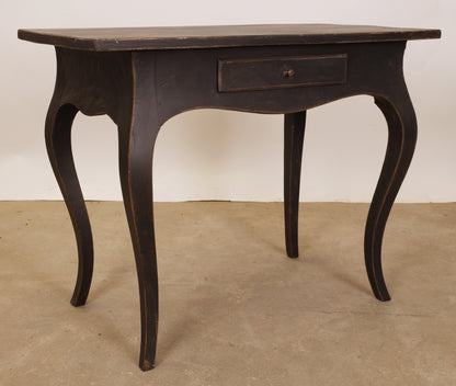 A black Rococo table with a drawer.