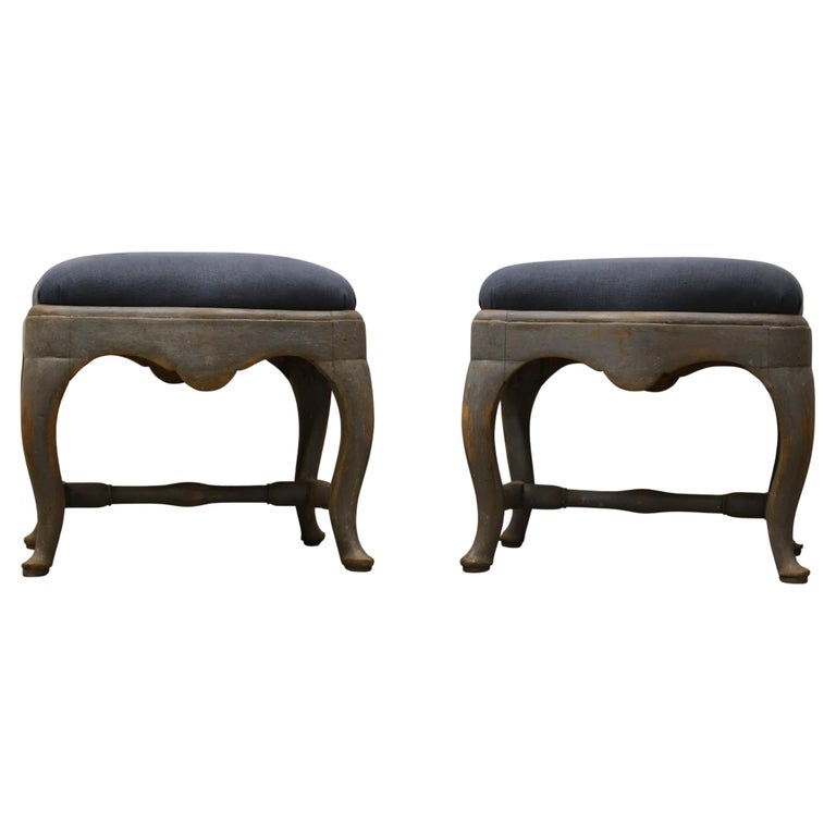 A pair of grey Rococo stools with blue fabric. White background.