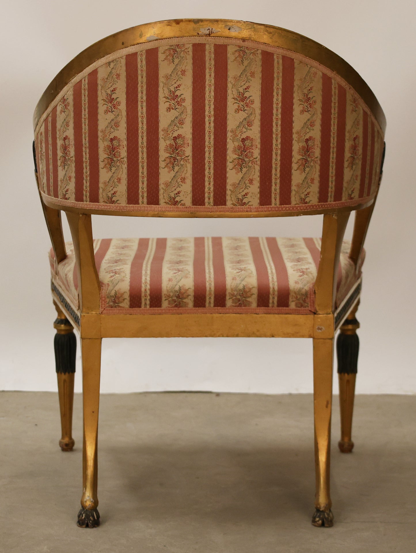 Back view of a gilded antique tub chair. 